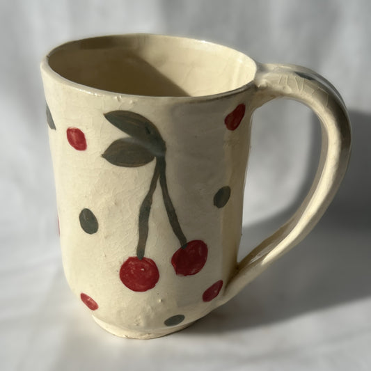 Ceramic mug with cherry design on a plain background