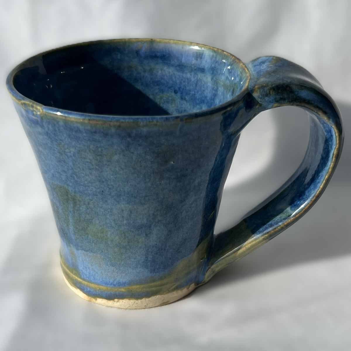 Blue ceramic mug with a handle on a white background with smooth surface