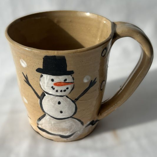 Ceramic mug with a snowman design on a tan background