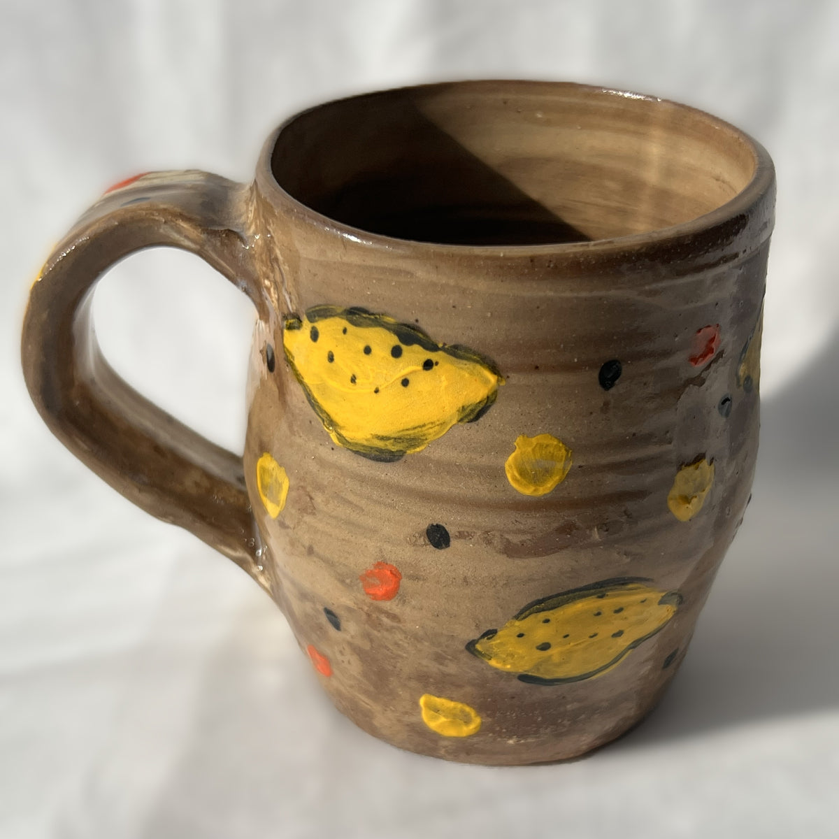 Brown Ceramic mug with lemon designs on a white background