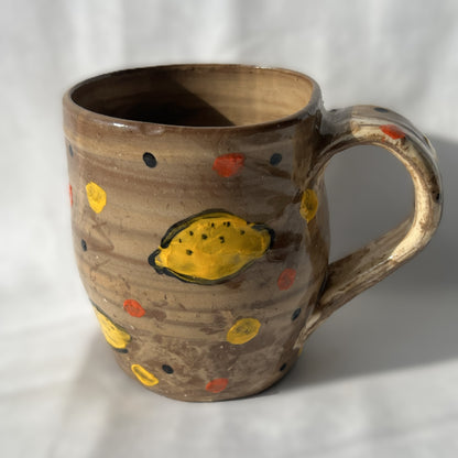 Brown ceramic mug with yellow lemon designs on a white background