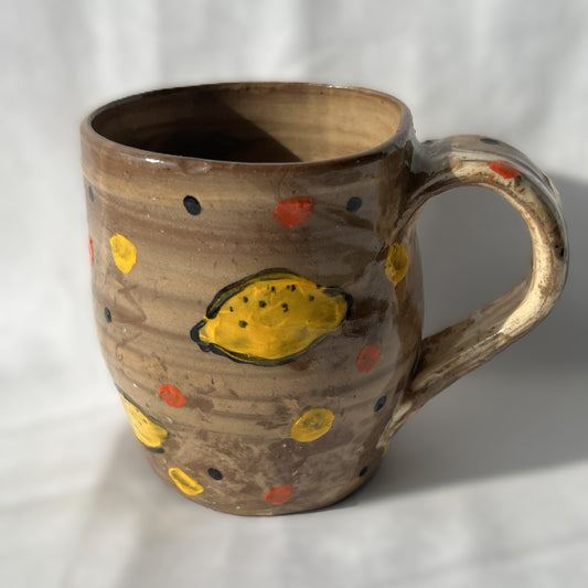 Brown ceramic mug with yellow lemon designs on a white background