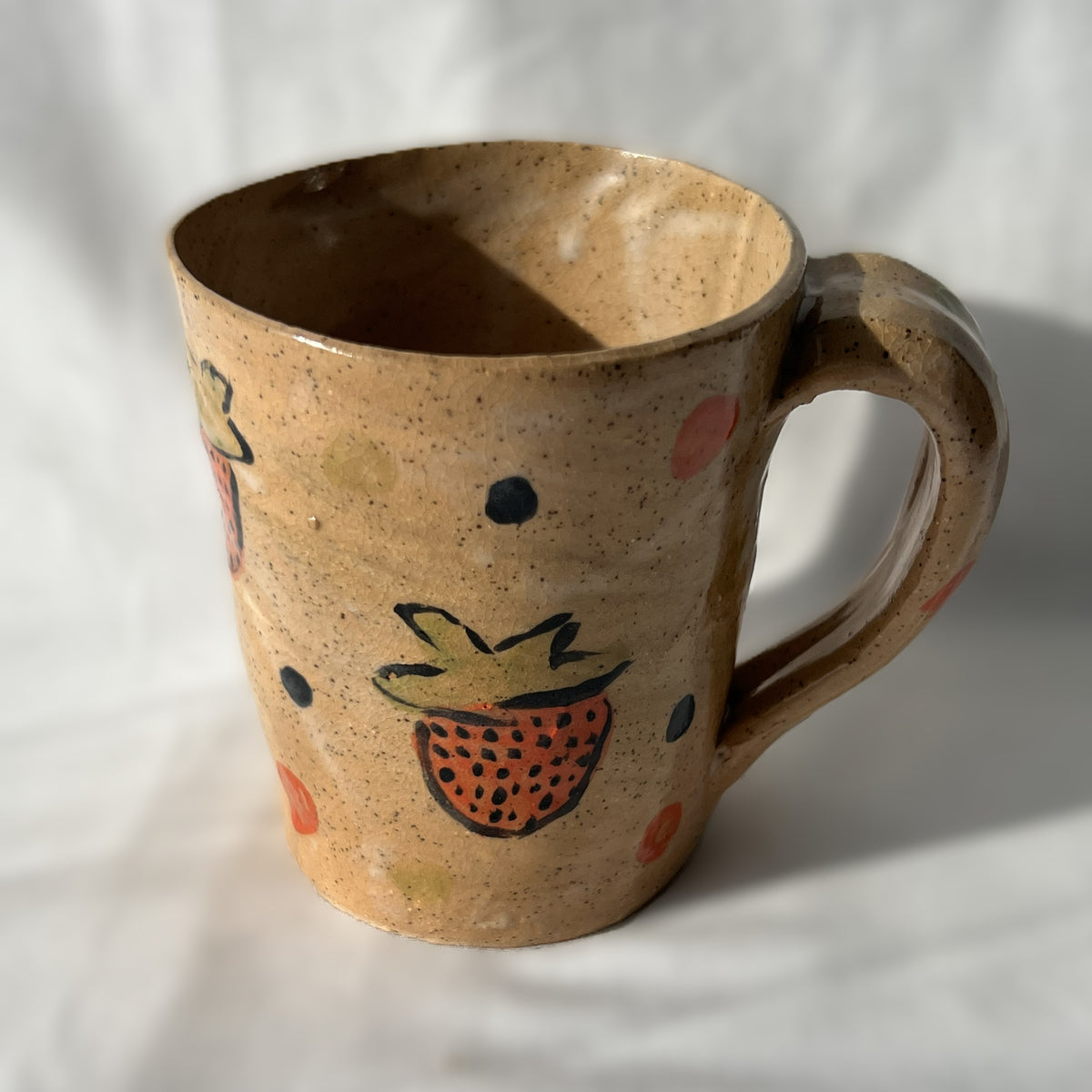 Ceramic mug with strawberry design on a speckled tan background