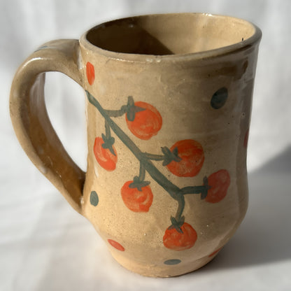 Ceramic mug with tomato design on a tan background