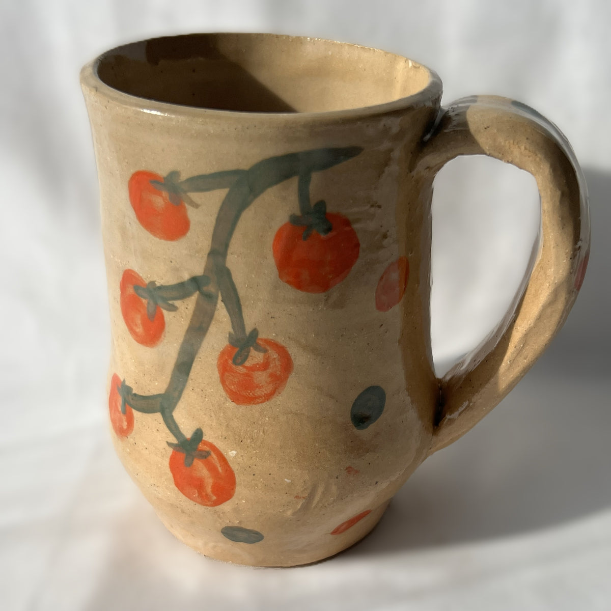 Ceramic mug with tomato design on a tan background