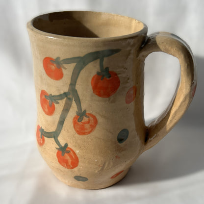 Ceramic mug with tomato design on a tan background