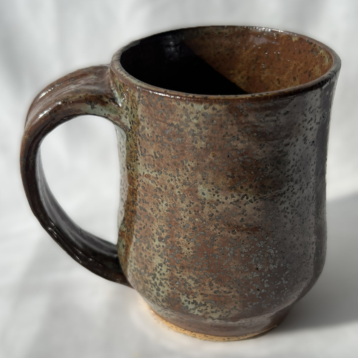 Brown ceramic mug with speckled texture on a white background