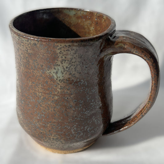 Brown ceramic mug with speckled glaze on a white background