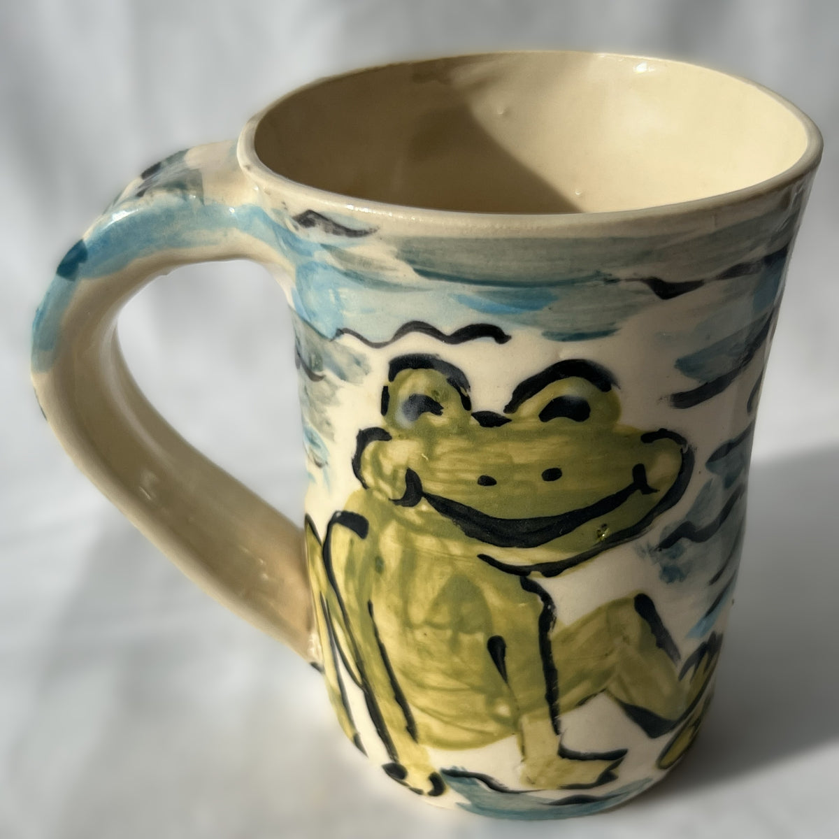 Ceramic mug with a frog design on a white background