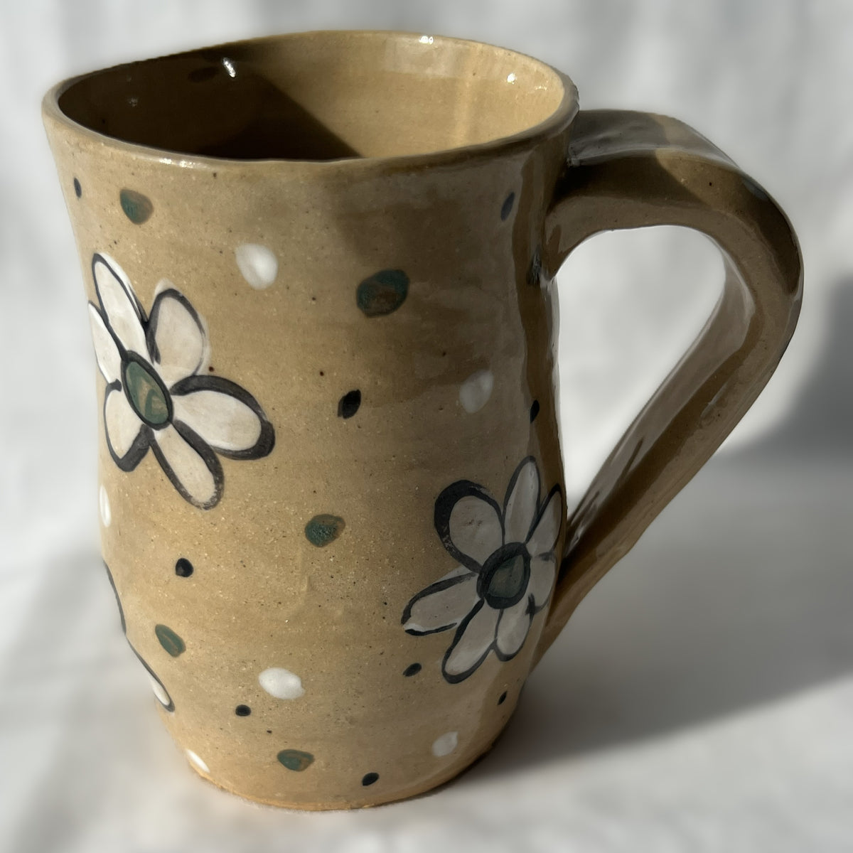 Ceramic mug with floral designs on a plain background