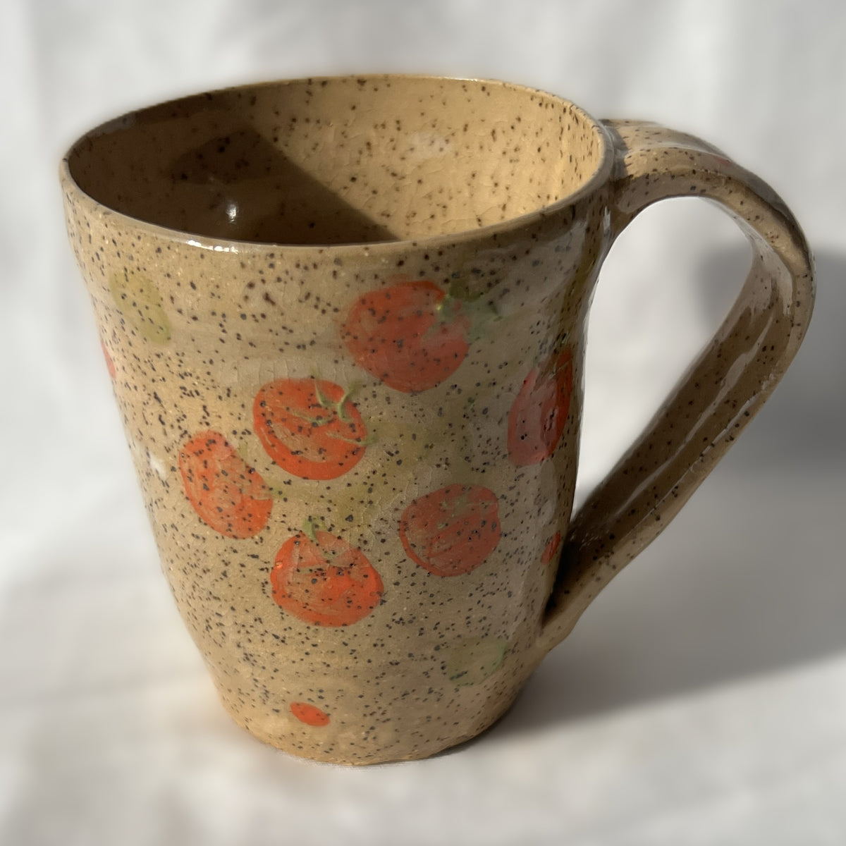 speckled Ceramic mug with tomato design on a tan background