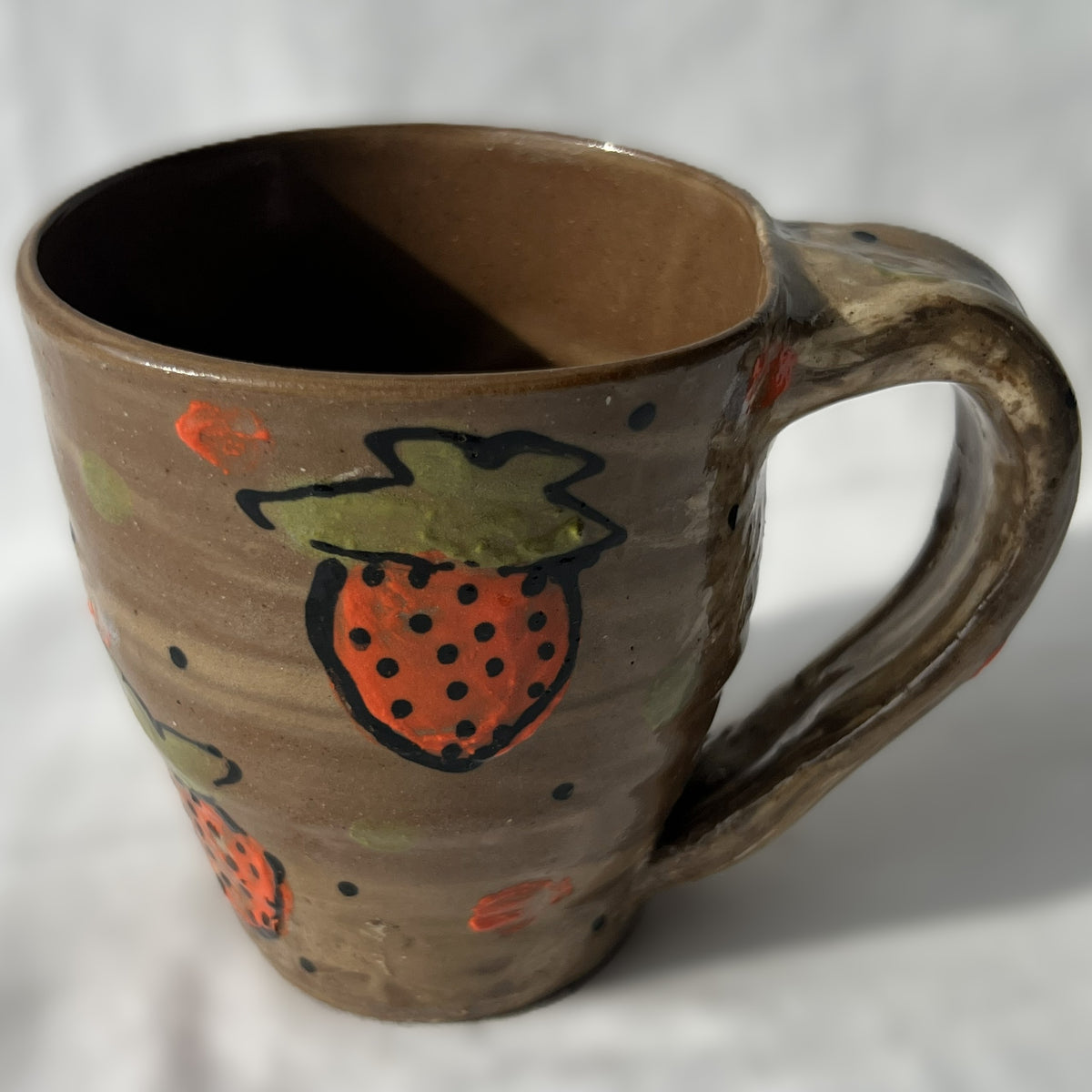 Brown ceramic mug with strawberry design on a white background