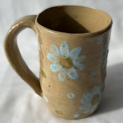 Brown ceramic mug with blue floral design on a white background