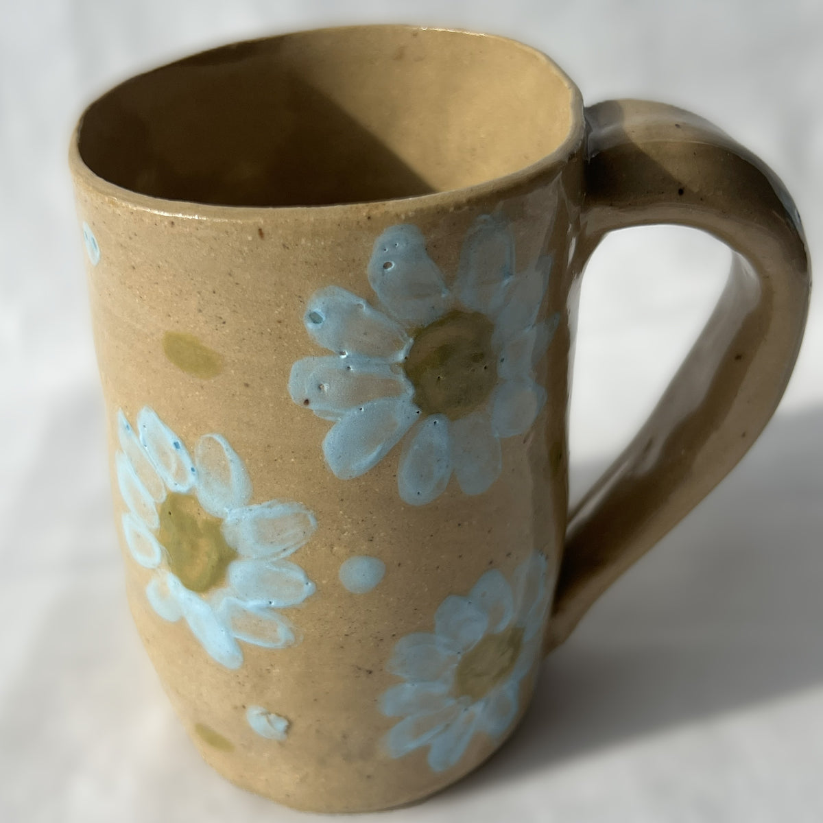 Brown ceramic mug with blue floral designs on a white background