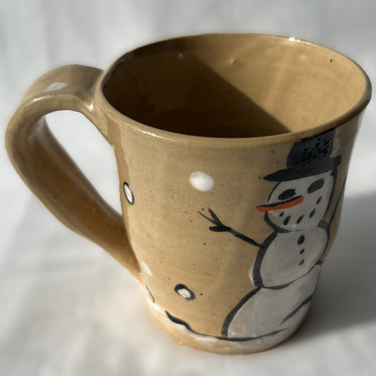 Ceramic mug with a snowman design on a tan background