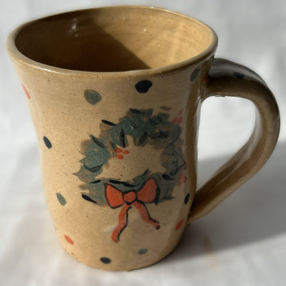 Ceramic mug with wreath design on a tan background