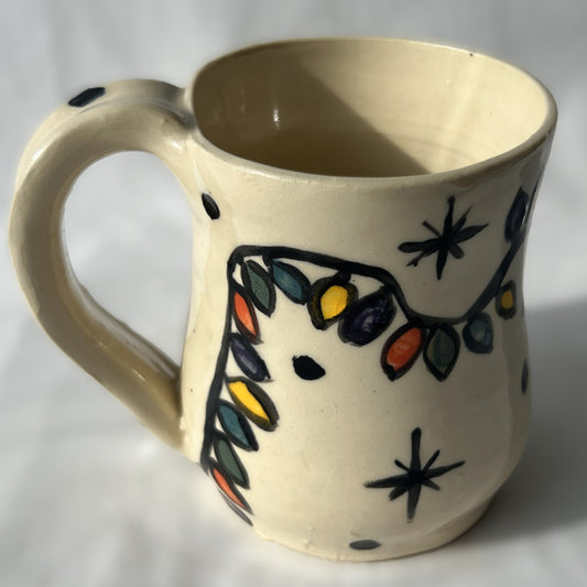 Ceramic mug with colorful Christmas light strand designs on a white background