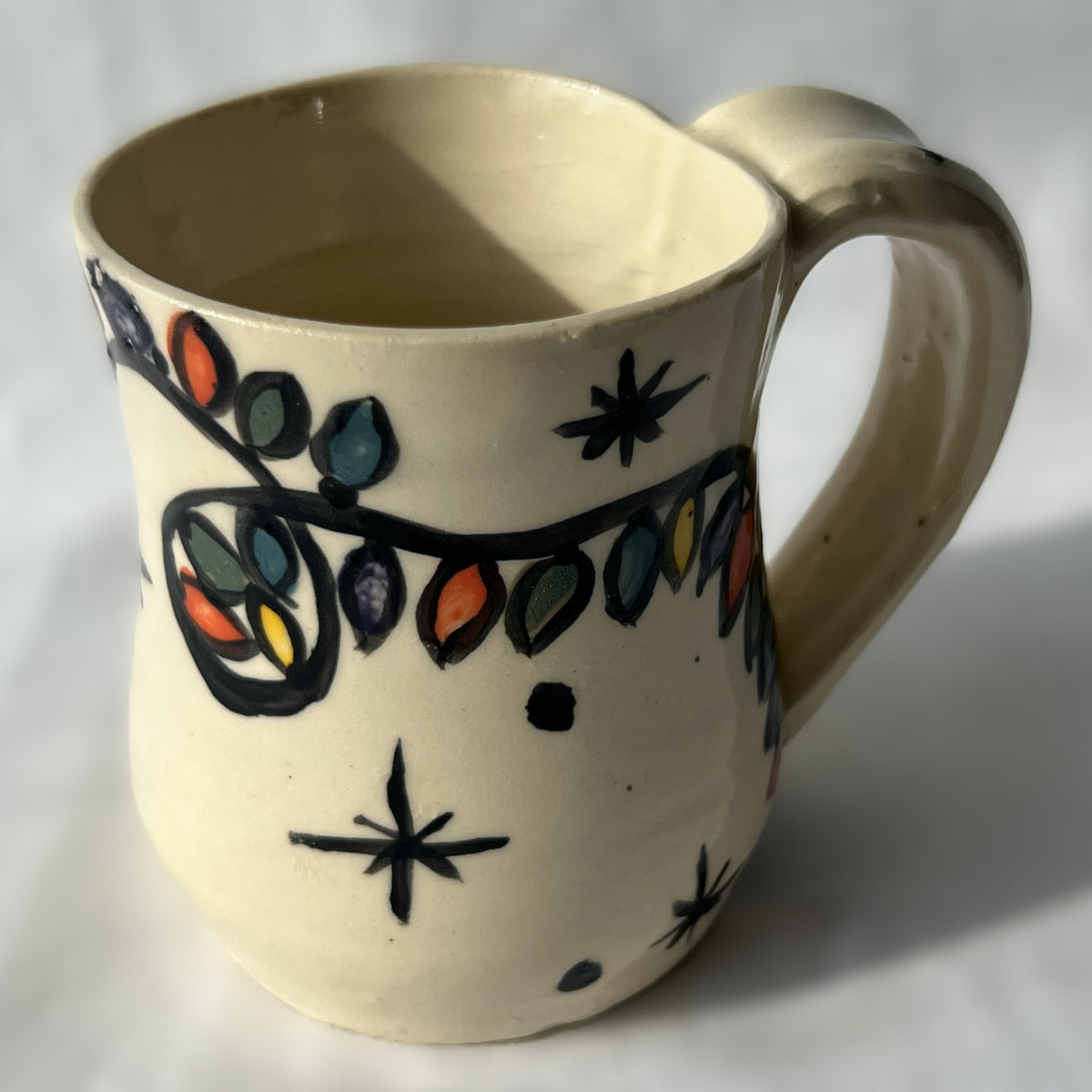 Ceramic mug with colorful Christmas light strand designs on a white background