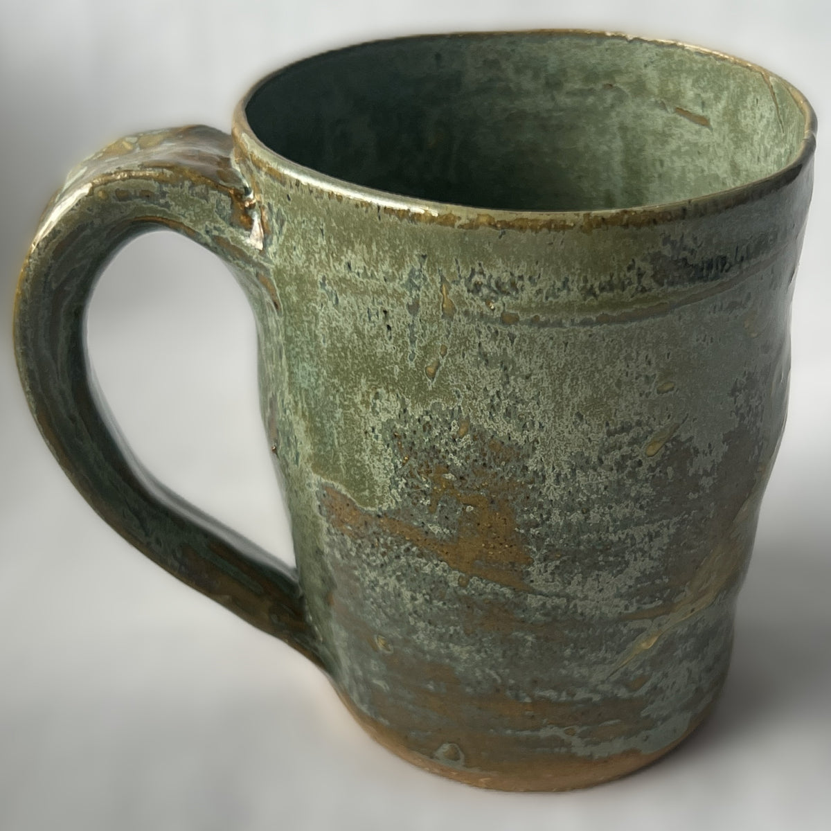 Ceramic Mug with a varied light green glaze that goes tan in some areas 