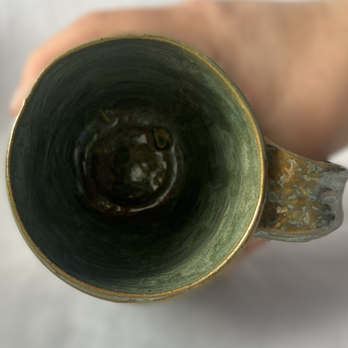 Ceramic Mug with a varied light green glaze that goes tan in some areas 