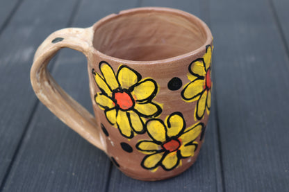 Ceramic mug with floral designs on a dark wooden surface