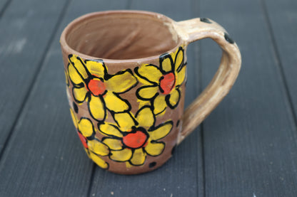 Ceramic mug with yellow floral patterns on a dark wooden surface