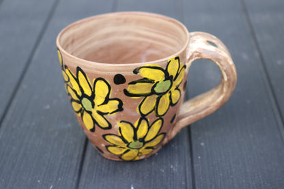 Ceramic mug with yellow floral designs on a dark wooden surface
