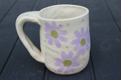 Ceramic mug with purple floral patterns on a dark wooden surface