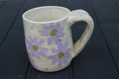 Ceramic mug with purple floral patterns on a dark wooden surface