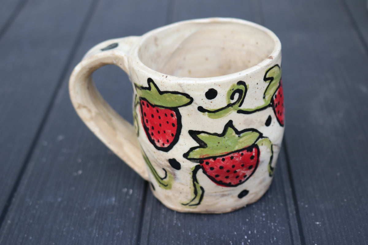 Ceramic mug with strawberry design on a dark wooden surface