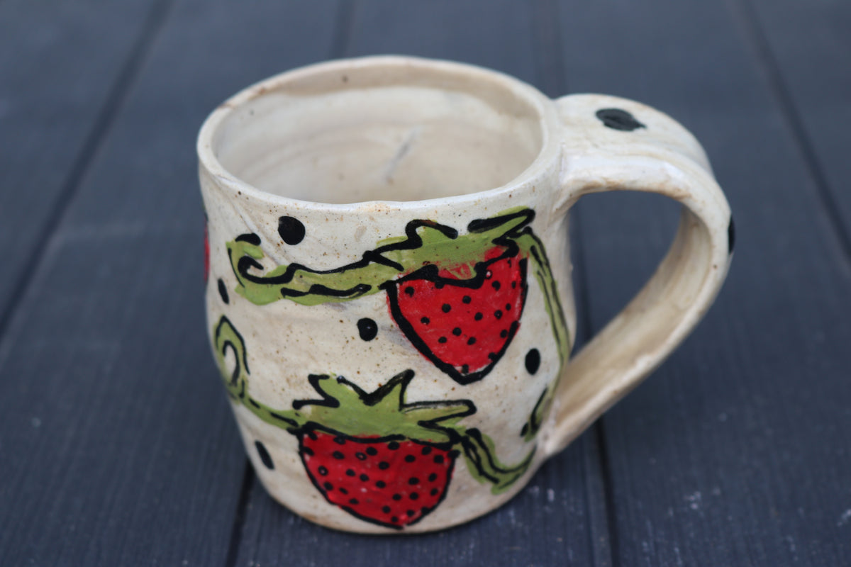 Ceramic mug with strawberry design on a dark wooden surface