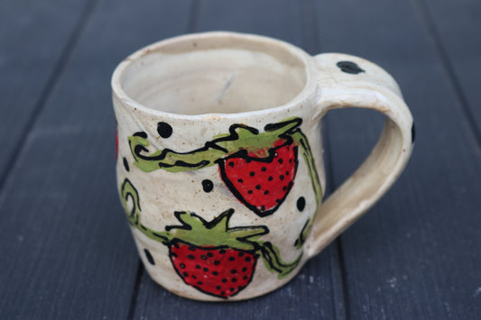 Ceramic mug with strawberry design on a dark wooden surface